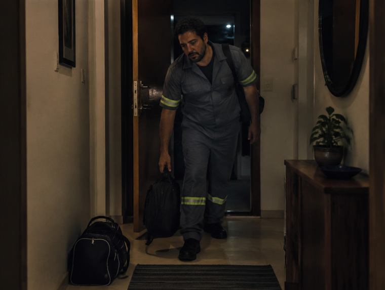 Homem cansado chegando em casa tarde, com a mochila da academia esquecida